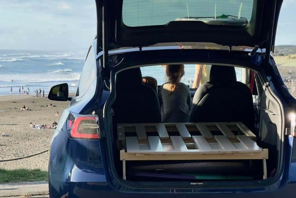 A girl sitting in the back of a car with an Auto Draft pallet in the trunk.