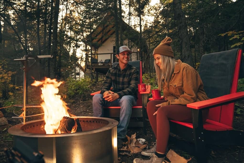 Two people enjoying a cozy fire pit at a new glampground in Minnesota.