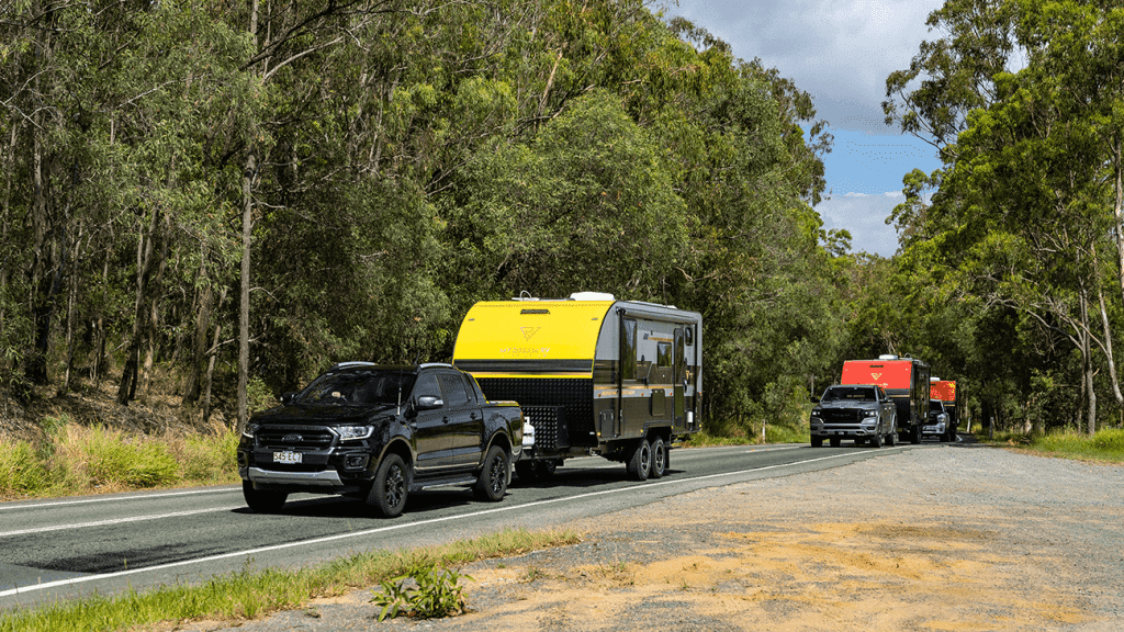 Two trucks towing a camper trailer down a country road in Australia's flourishing caravan industry.