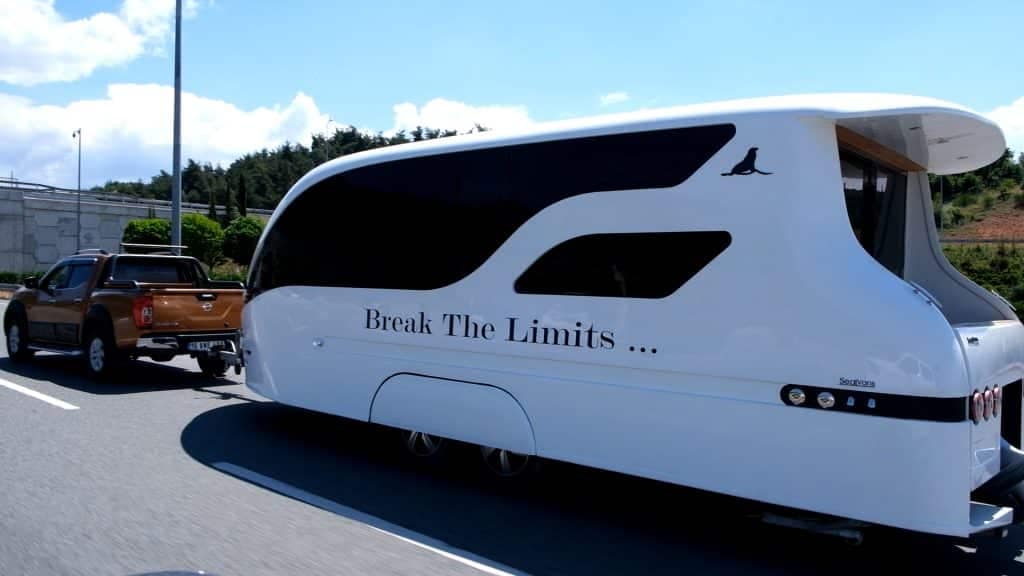 A Modern Adventurer is driving a white truck down the road with a trailer attached to it.