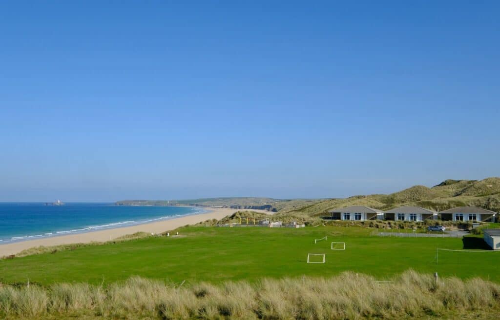 A Beachside Holiday Park situated on a grassy field near the ocean, offering a serene retreat for campers and contributing to the development of the local economy.