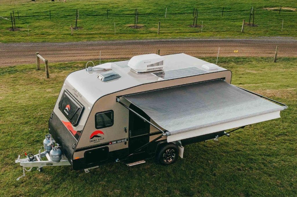 A Snowy River camper trailer parked on a grassy field.