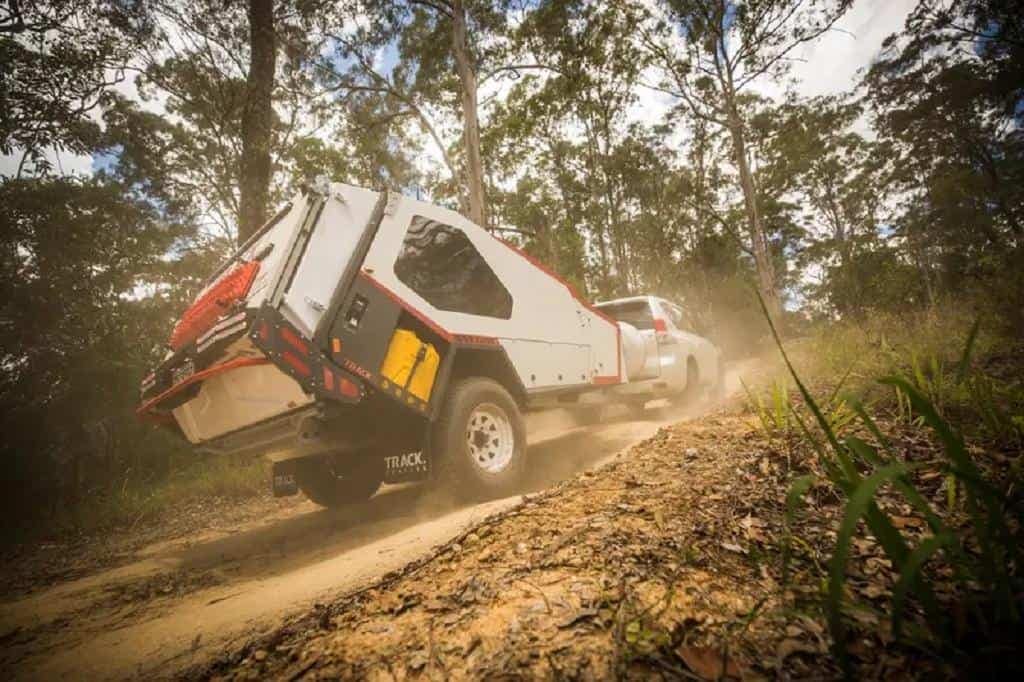 A Track Trailer driving down a dirt road in the woods.