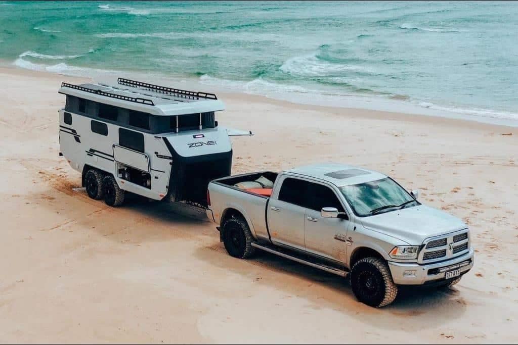 An RV Manufacturing truck towing a 3D Printed Caravan on the beach in Australia.