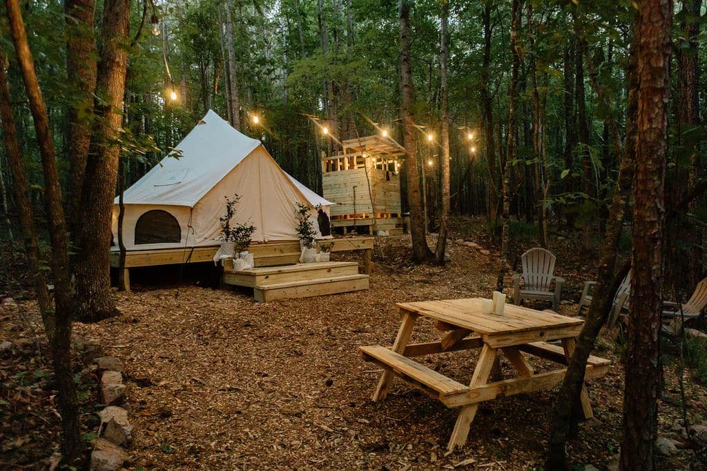 A sustainable and eco-conscious tent nestled in the woods, complete with a picnic table for customer engagement.