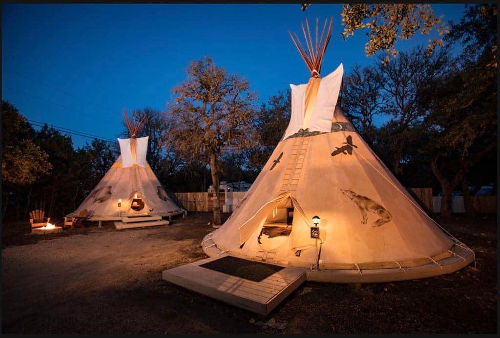 Two teepees at Mystic Quarry are lit up at night.