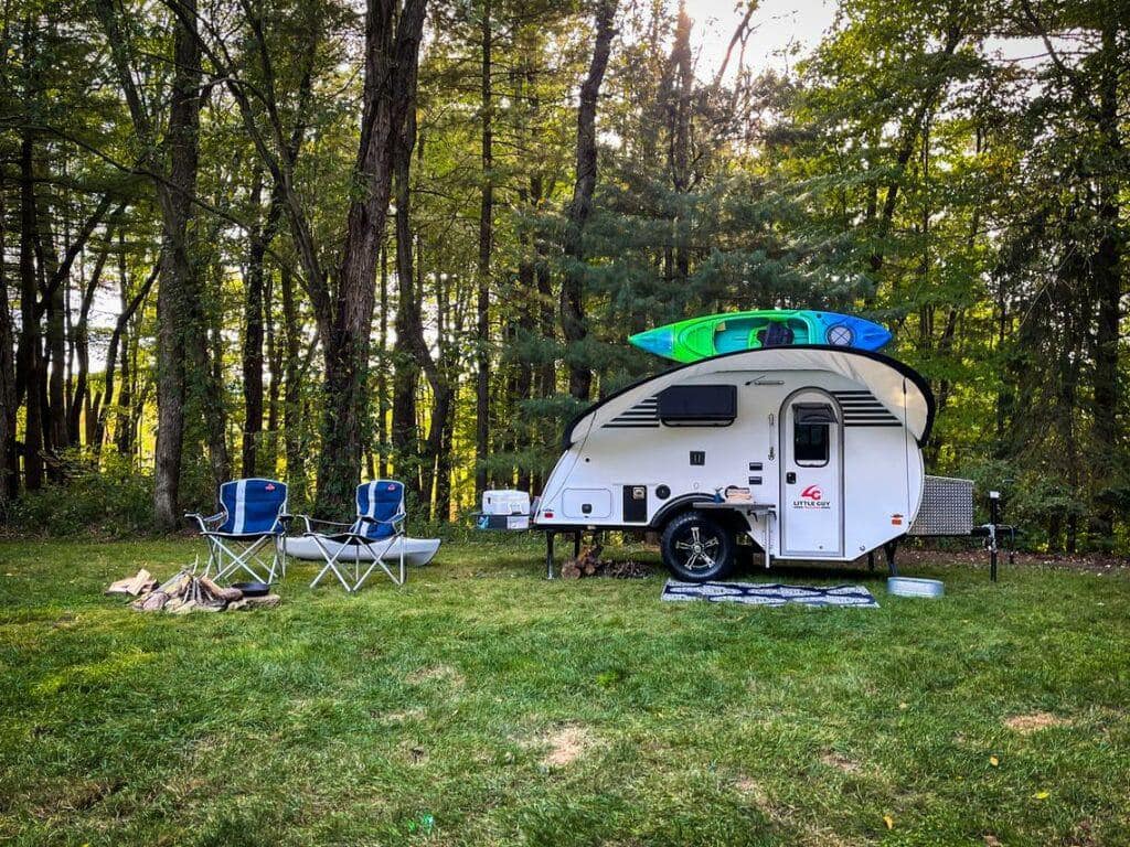 A compact trailer parked in the woods, ready for adventures.