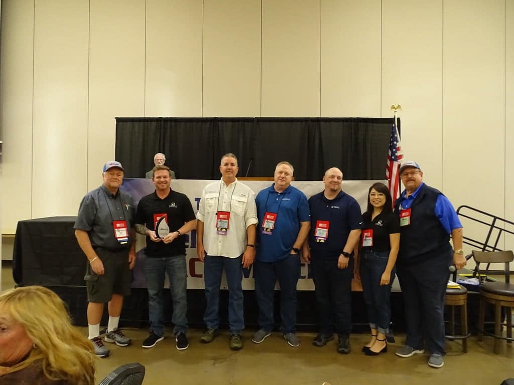 A group of people standing next to each other at a Texas Camping Scene convention.