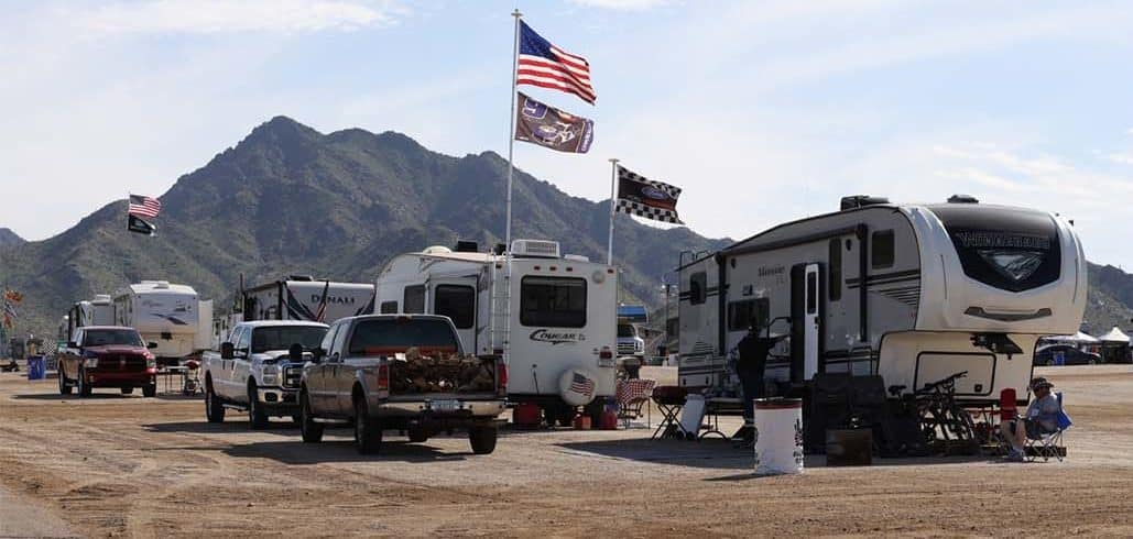 A group of RVs parked in a parking lot, including RVnGO, the Official RV Rental Partner for Phoenix Raceway.