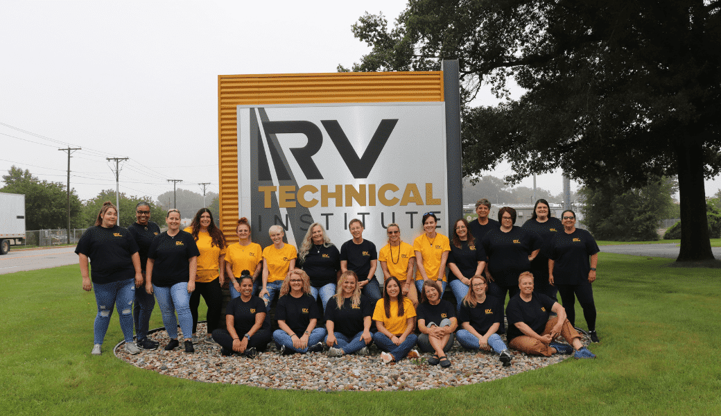 A group of people posing in front of a sign that says RV Technical Institute, exceeding their recruitment goal for the year.