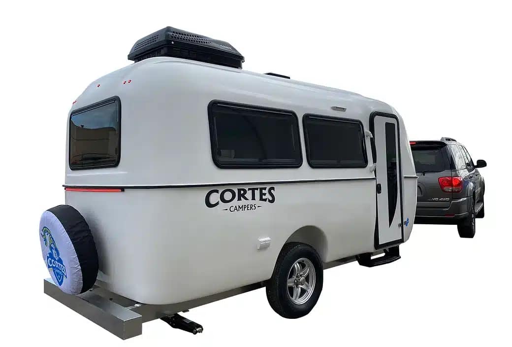 A small camper trailer with a car attached to it, available for rent from Cortes Campers.