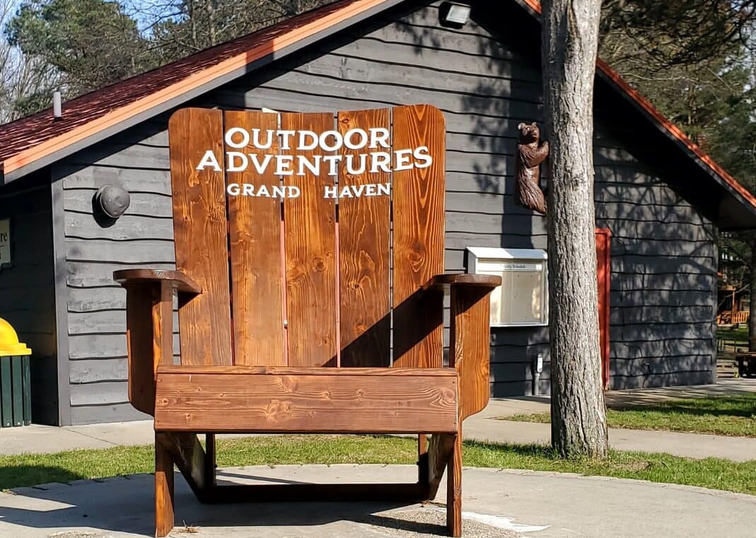 An outdoor adventures campground featuring an adirondack chair in front of the Grand Haven Resort's Camp Store building.