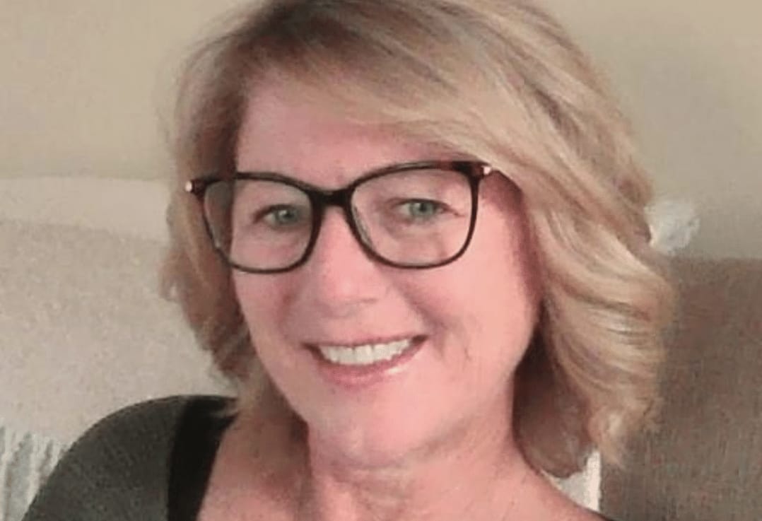 A smiling elderly woman with blonde hair wearing glasses and a green sweater, sitting indoors, labeled as "Auto Draft.