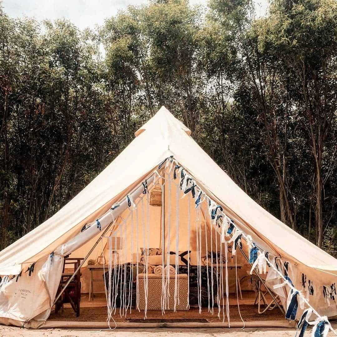 A personalized white tent sitting in the middle of a wooded area, perfect for glamping in an Australian setting.