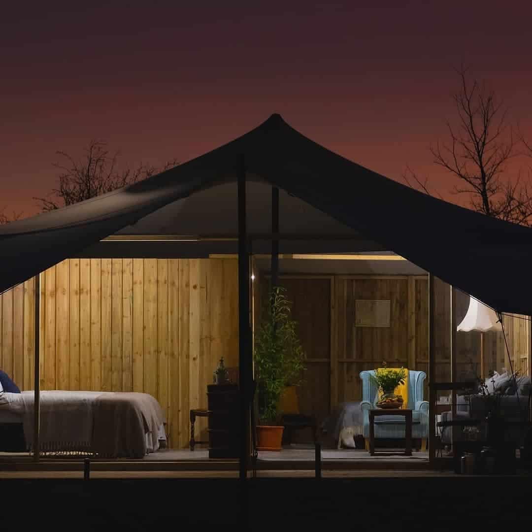 A kid-friendly glamping site with luxurious UK country hotel-like tents in the night.