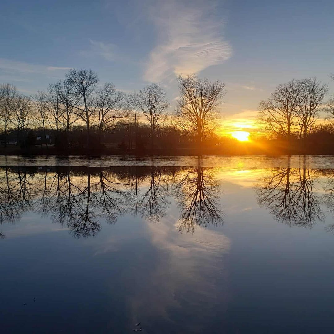 Revitalization: The sun reflects off the tranquil surface of a body of water, revitalizing the surroundings at ECO Lake Park.