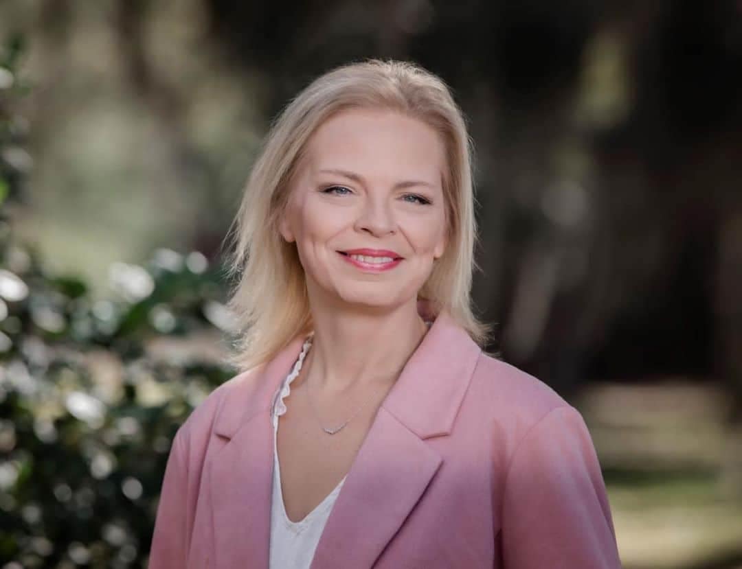 A blonde woman, VP of Operations at Four Points RV Resorts, in a pink blazer and white shirt.