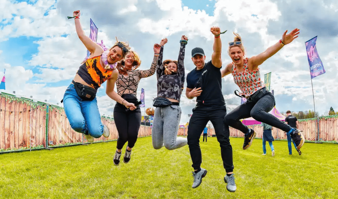 A group of people jumping in the air at a music festival, exhilarated by their collaborative efforts.