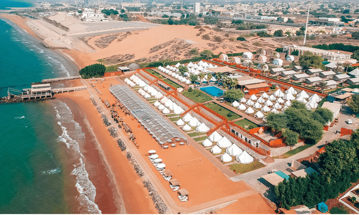 An aerial view of Longbeach Campground, located in Ras Al-Khaimah, UAE. The beach is adorned with white tents, offering a picturesque scene for visitors after its September