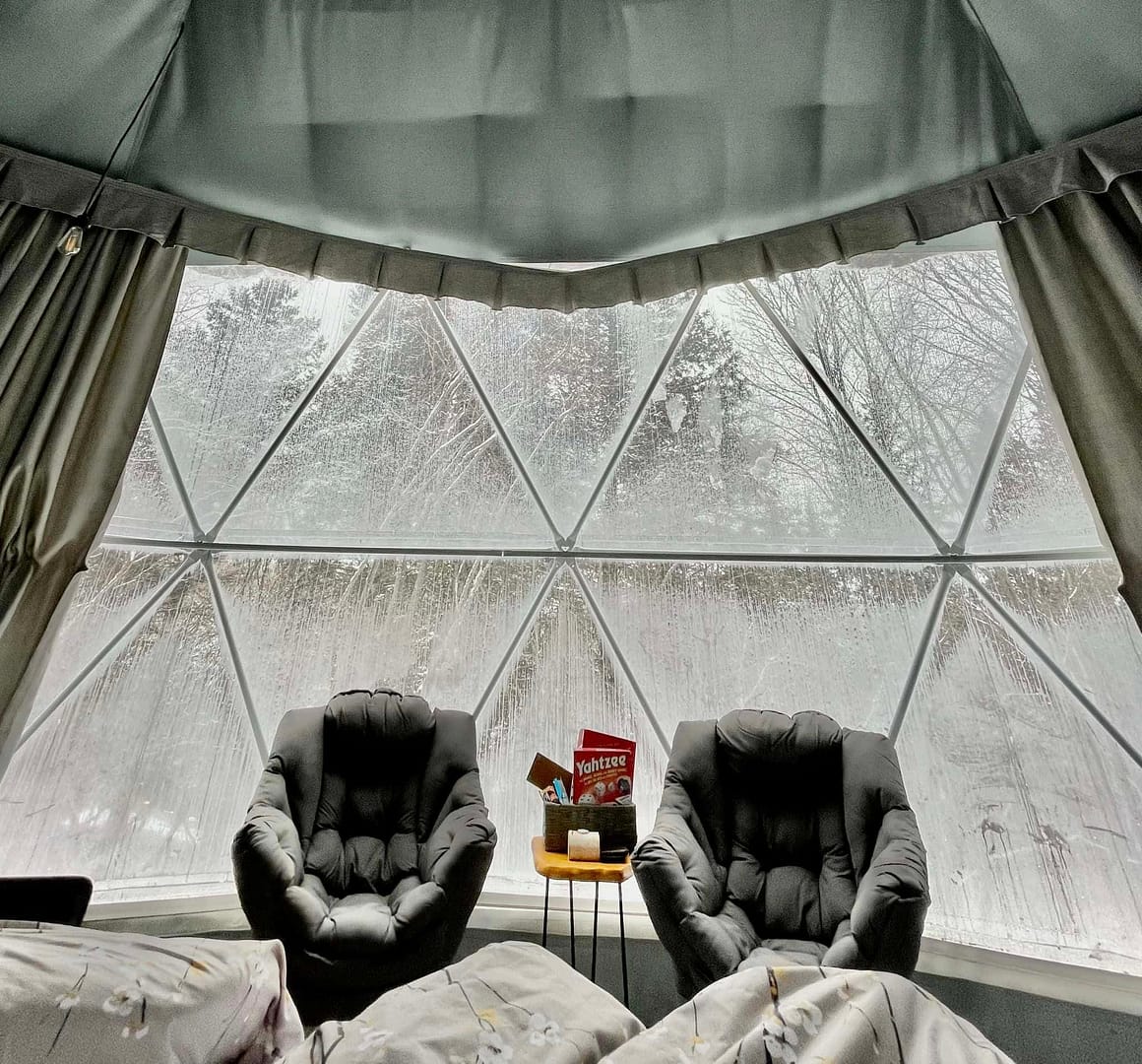 A glamping resort room with two chairs in front of a large window, offering serene views of the surrounding Blackstrap Provincial Park.