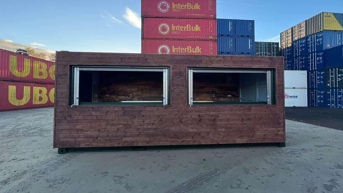 A wooden shipping container in front of a glamping resort.
