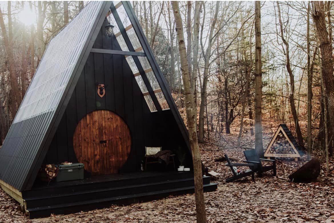 A black tepee in the luxury camping woods of Fennville, Michigan, with a door.
