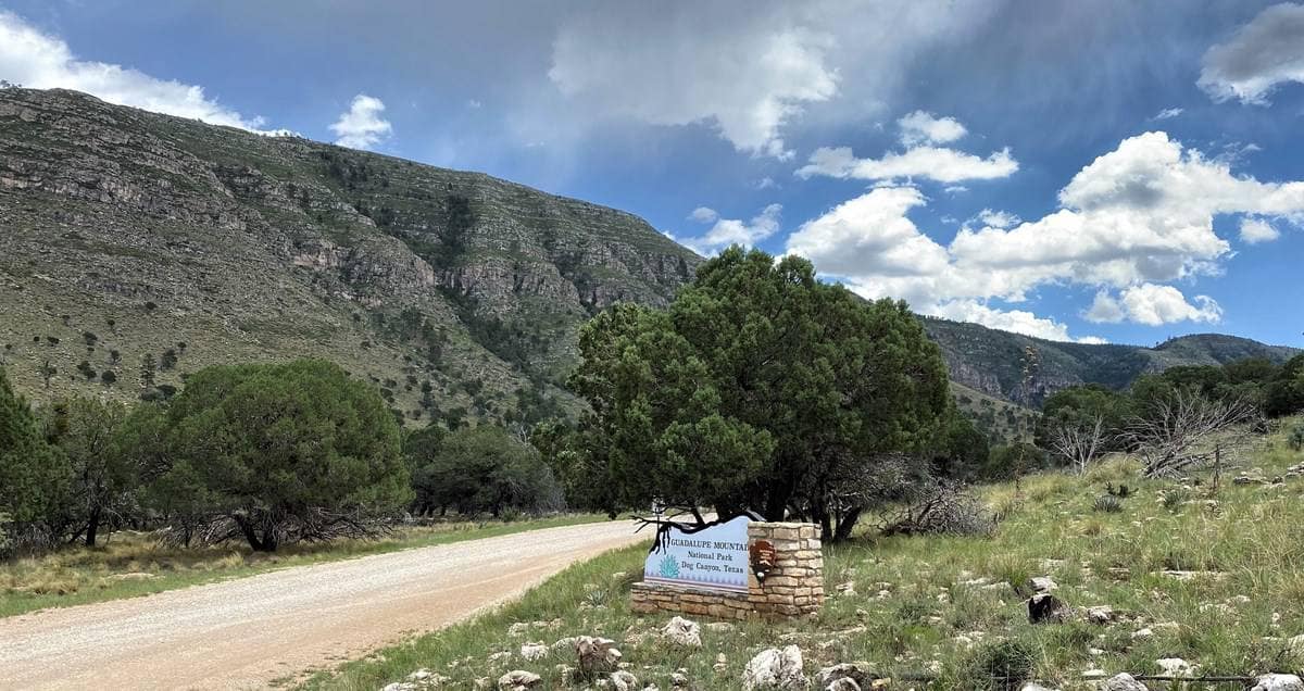 A dirt road with a sign in front of the Guadalupe Mountains National Park.