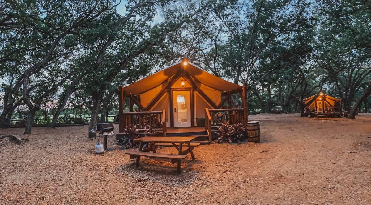 Two country western-themed tents surrounded by trees at dusk.