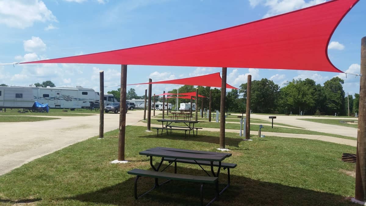 Jenkins Organization campground with picnic tables under a red shade sail.