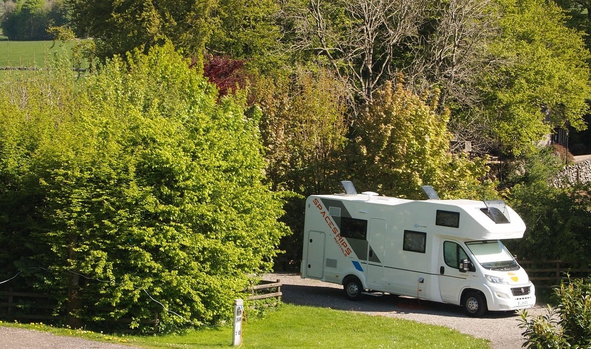 A white Spaceships RV parked on a gravel road, in an exclusive partnership with the Caravan and Motorhome Club.