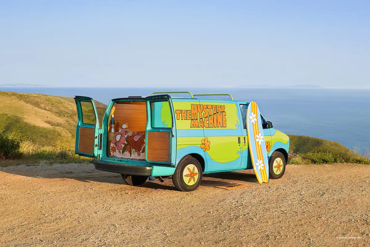 Mystery Machine van with Scooby-Doo parked on a dirt road.