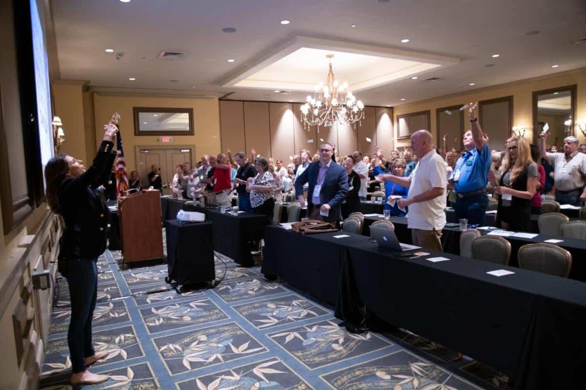 Attendees at the FRVCA Conference eagerly gather around a table in the room to wrap up the event with record attendance.