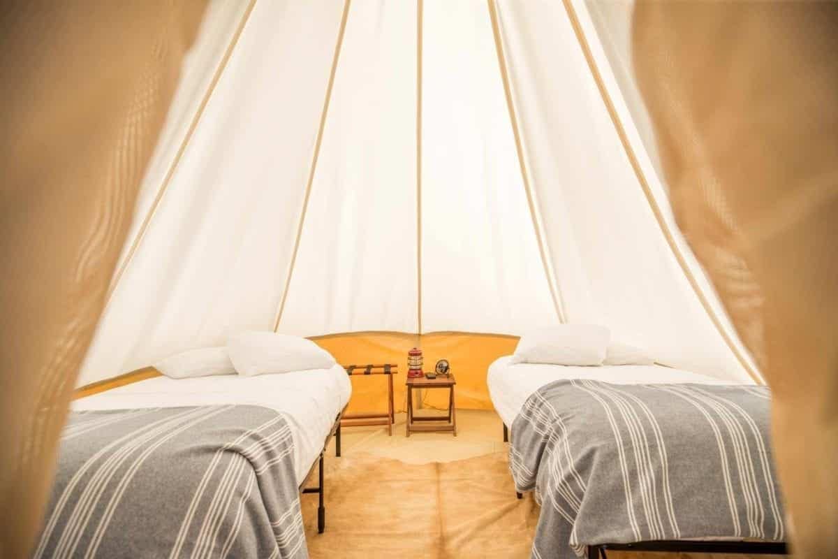 A cozy bed in an Under Canvas tent, adorned with a soft blanket.