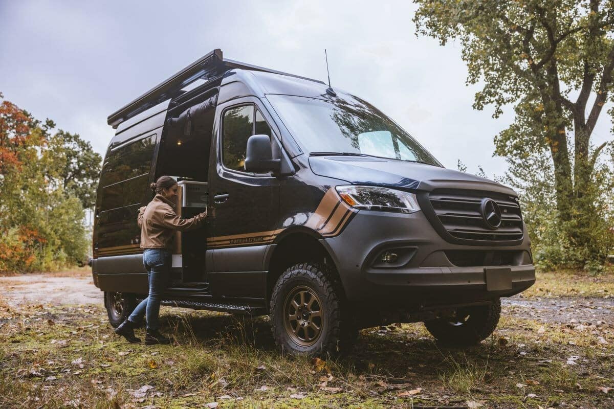 A woman opens the door of a Mercedes-Benz Sprinter RV from the MODE Adventure Van Lineup.
