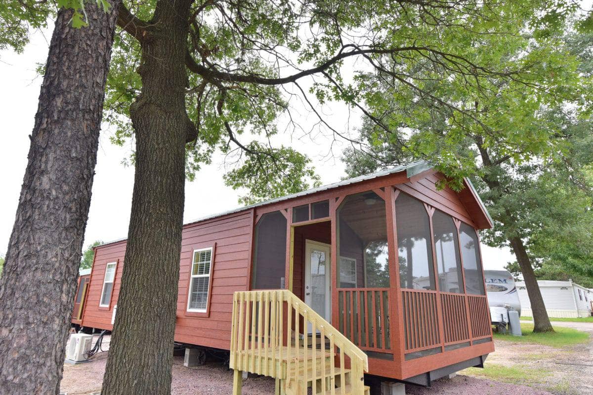Nestled within Bonanza Camping Resort is a quaint red cabin boasting enduring charm, complete with a screened-in porch.