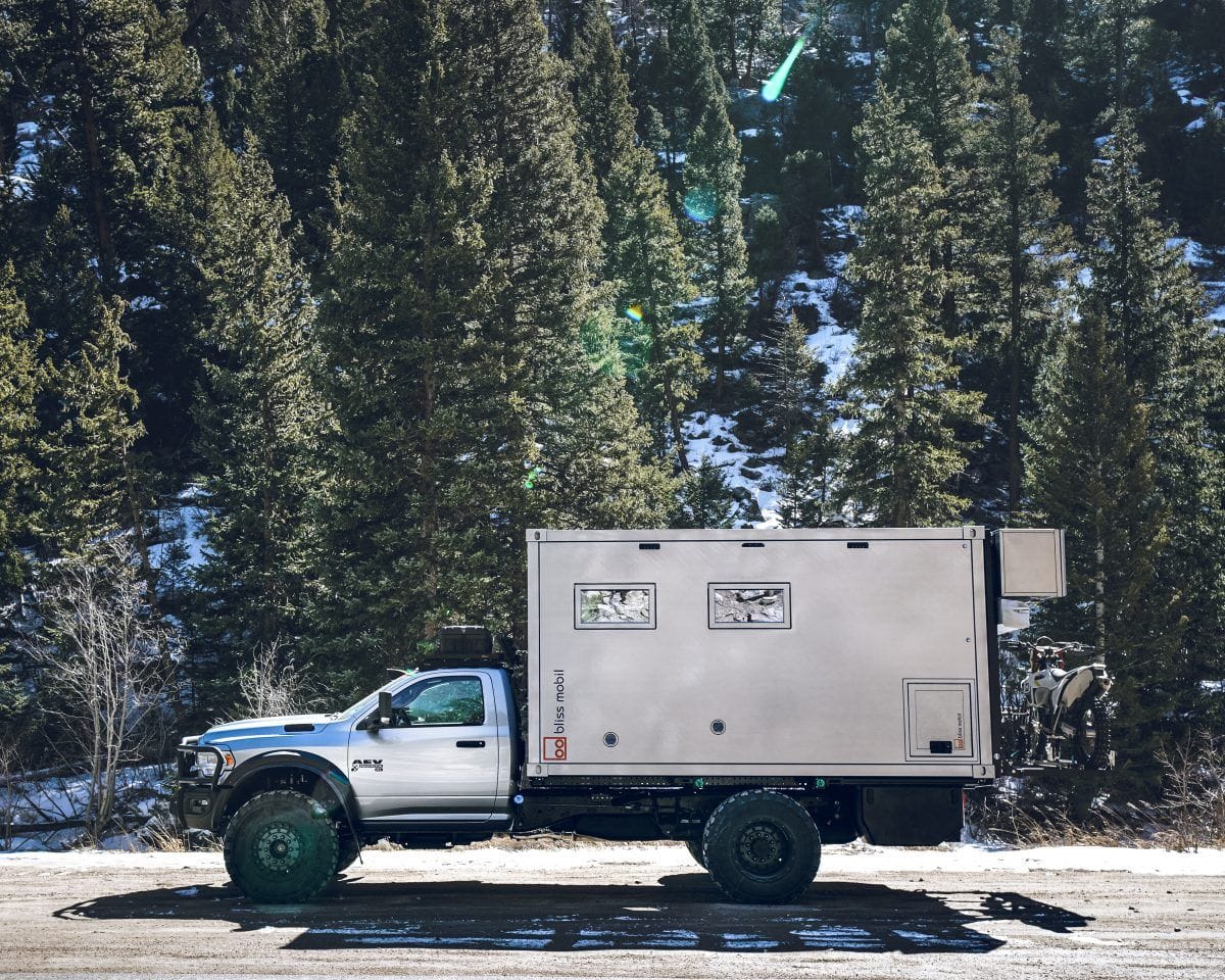 An AEV truck with a camper parked on the side of the road.