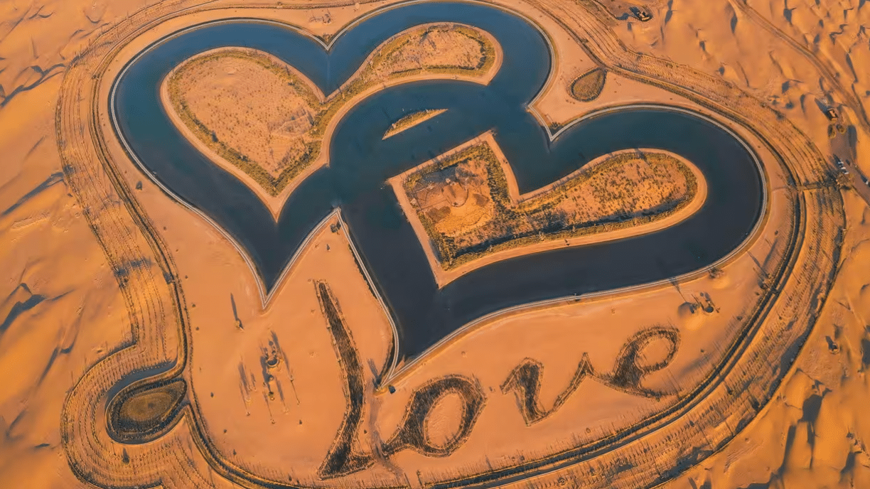 Two hearts shaped like a heart in the sand at Love Lake, Al Qudra's Romantic Getaway.
