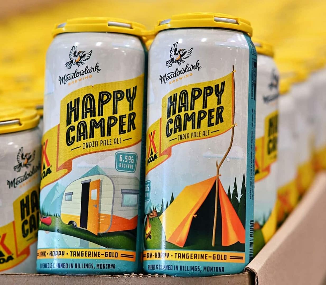 Three cans of happy camper beer in a Meadowlark Brewing box.