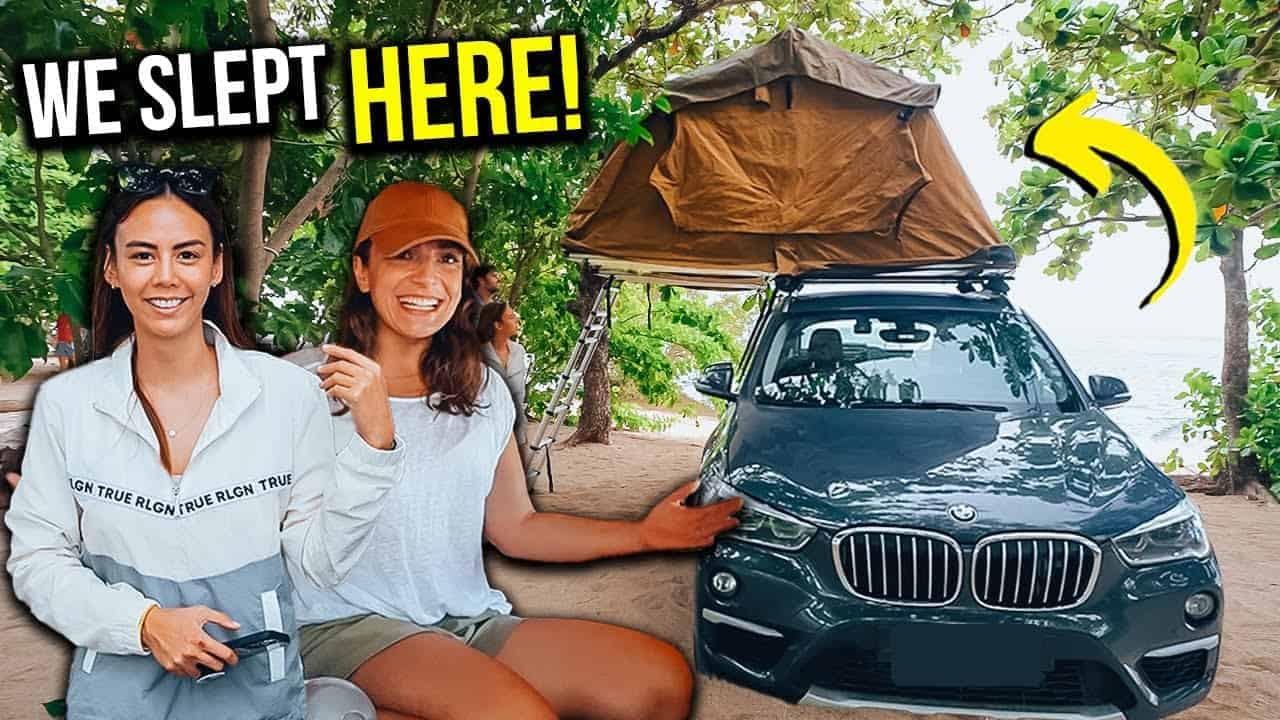Two women from the Philippines standing next to a BMW X3 and a tent, ready for their camping adventure.