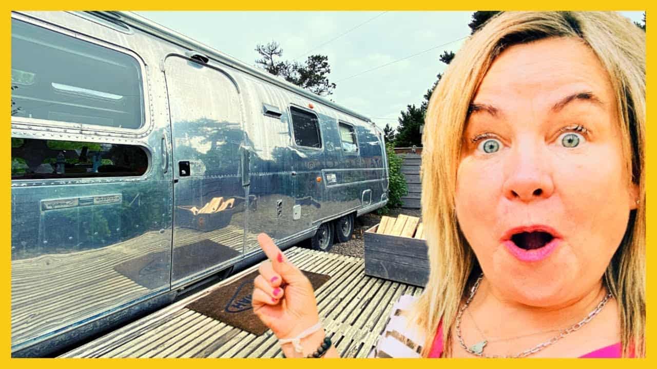 A woman is posing in front of an Airstream trailer.