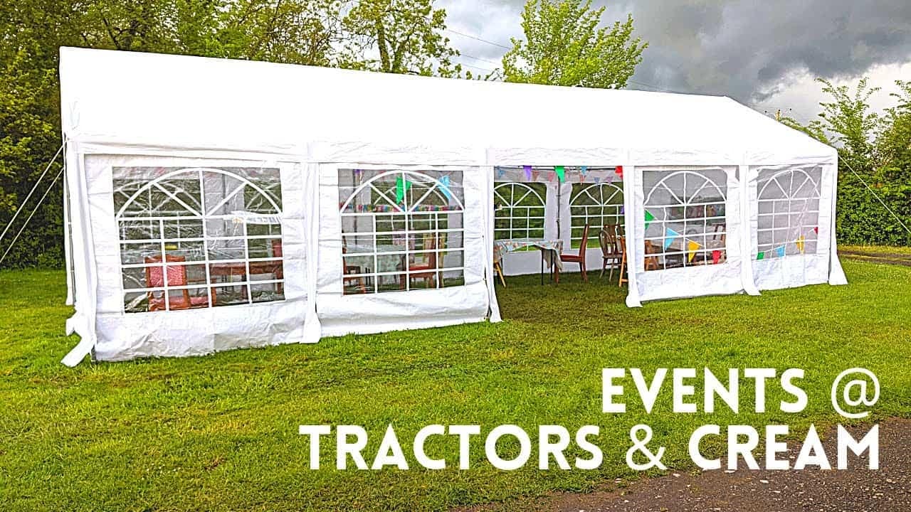 A white marquee tent set up for events, with the words "events tractors & cream.