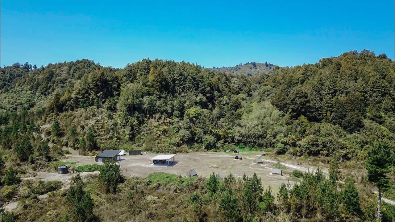 An aerial view of a forest with a house in the middle, nestled in the Middle of Nowhere.