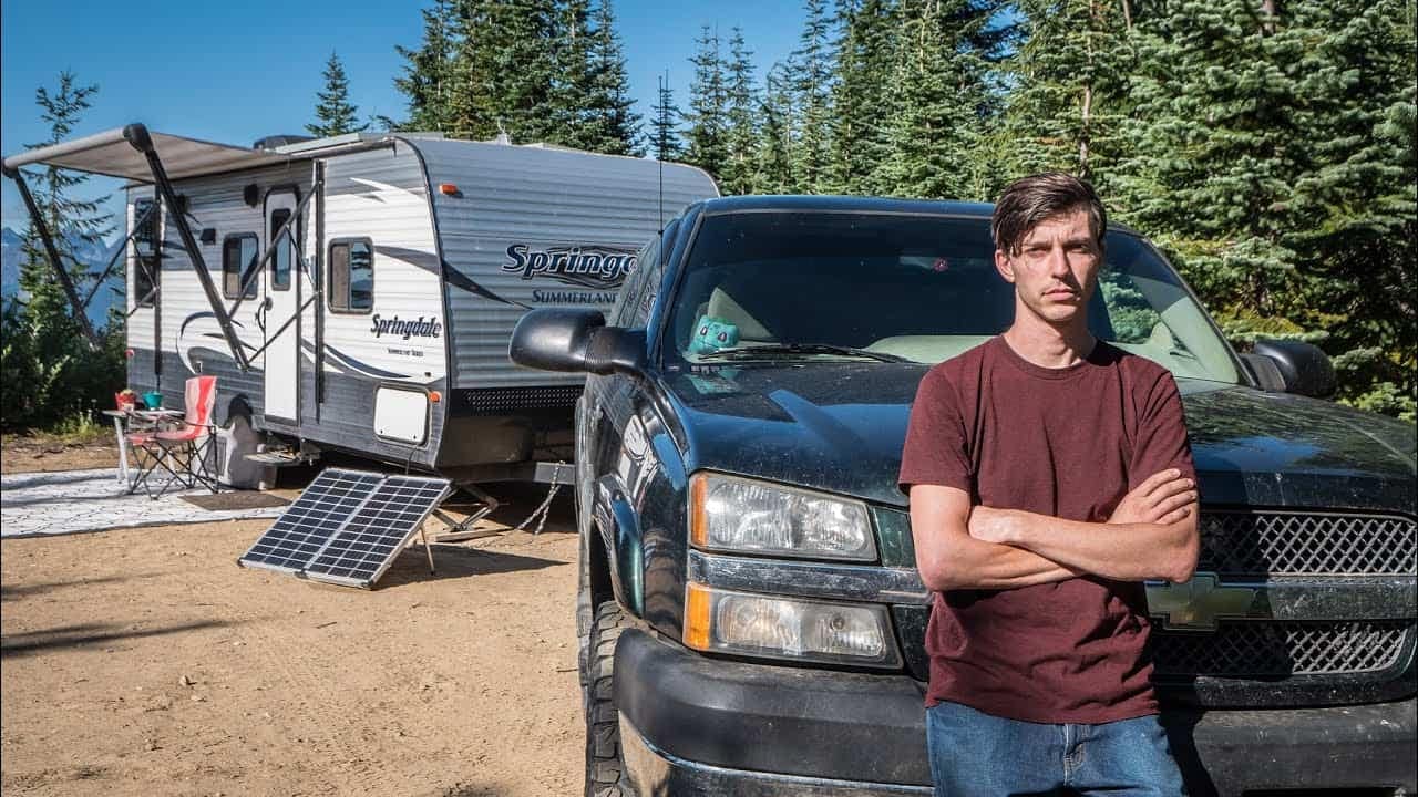 A man standing in front of an RV equipped with solar panels.