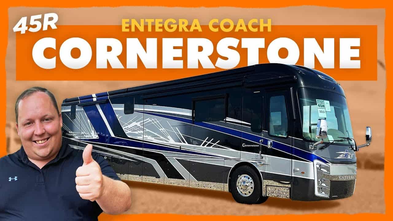 A man is giving a thumbs up to a 2022 Entegra Coach Cornerstone 45R RV.