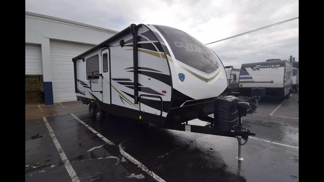 A black and white Keystone Outback RV parked in a parking lot.