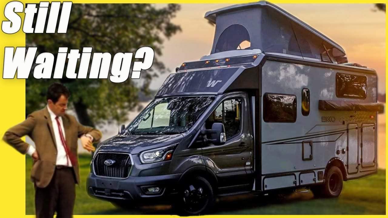 A man is standing next to a Winnebago RV, with the words "Still Waiting?" written on it.