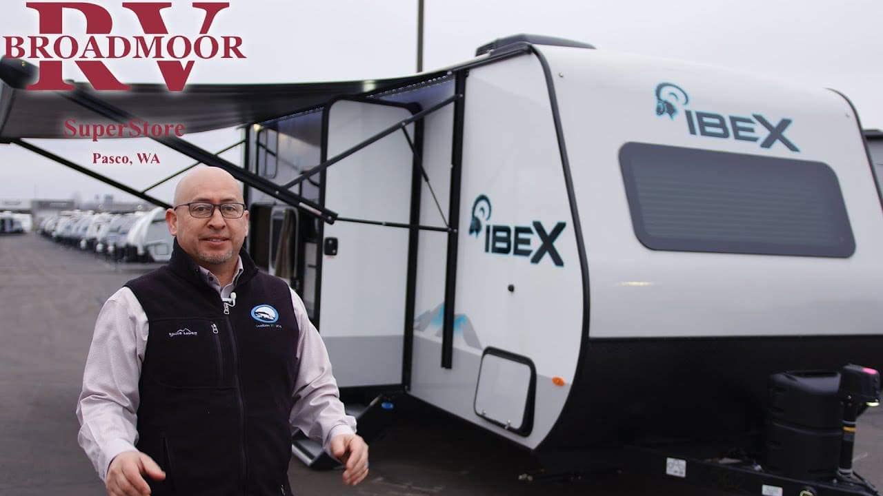 A man standing in front of a 2022 Forest River IBEX 19MBH RV in a parking lot.