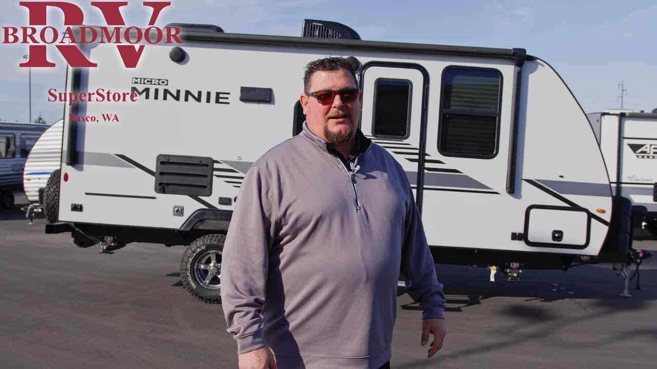 A man is standing in front of a Winnebago camper trailer.