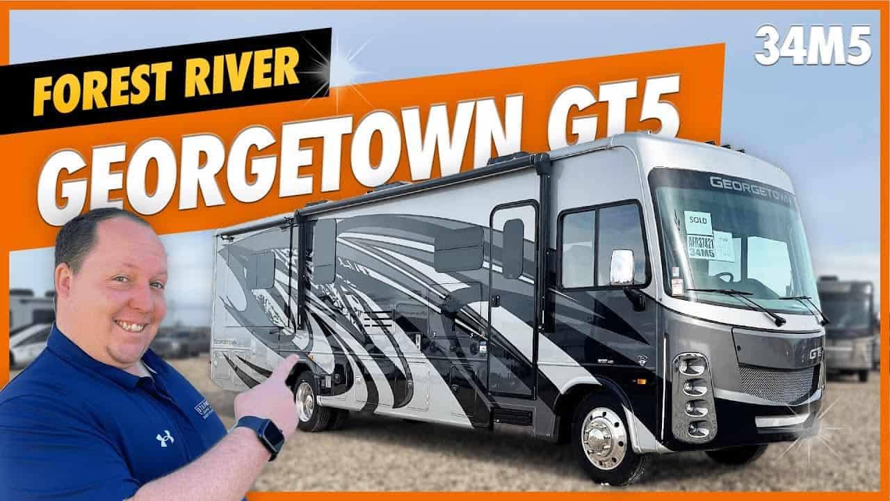 A man is standing in front of a Forest River Georgetown GT 5 34M5 RV with the text "Forest River" on it.