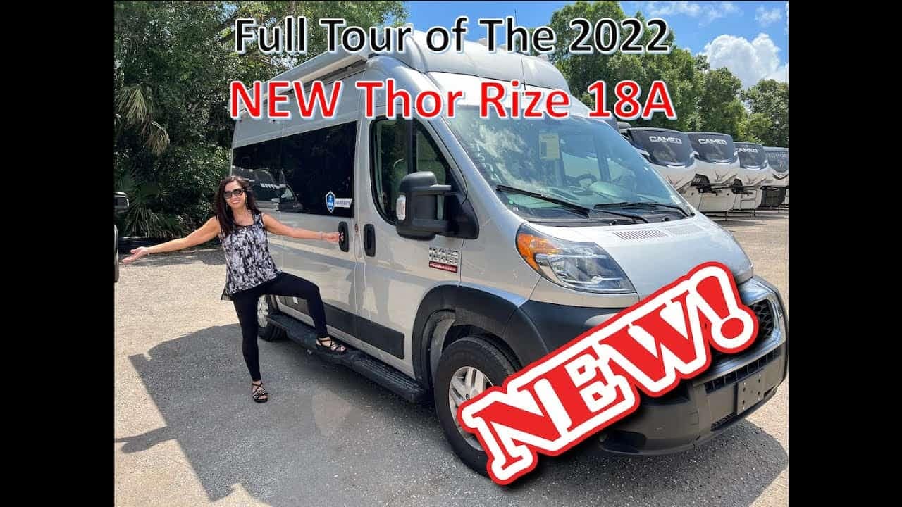 A woman is posing in front of a van with the words full tour of the 2020 Thor Rize.